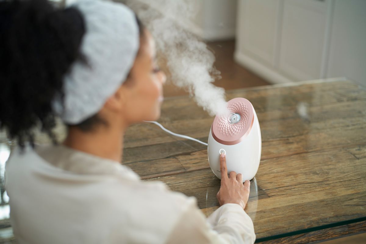 Frau genießt Dampfanwendung mit moderner Gesichtssauna – effektive Hautpflege und Tiefenreinigung im eigenen Zuhause